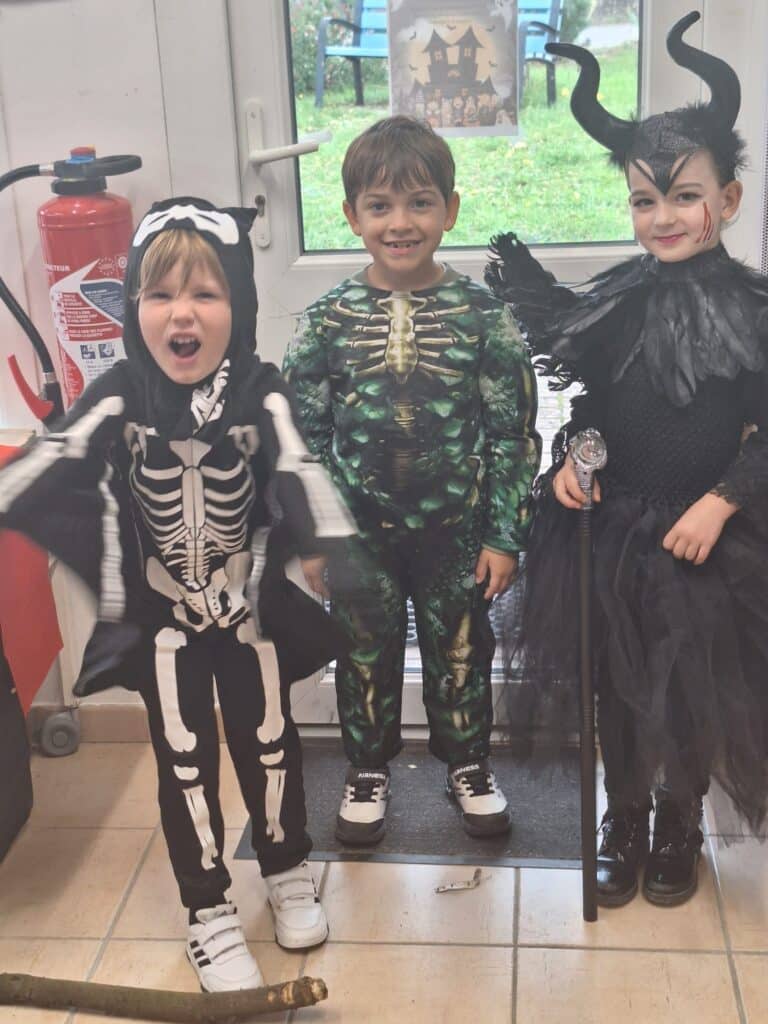 Trois enfants déguisés pour Halloween : un squelette, un monstre vert musclé et une petite sorcière maléfique