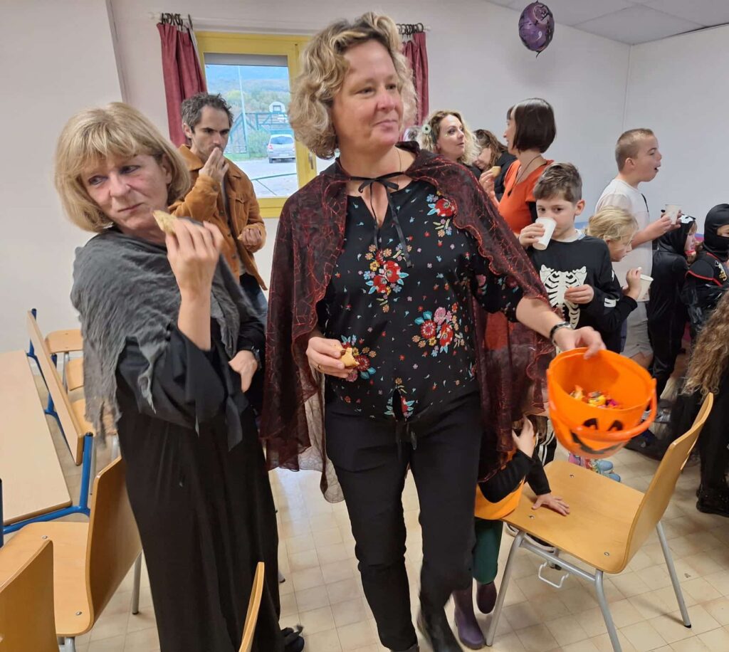 Une bénévole distribue des bonbons tandis que les enfants dégustent le goûter d’Halloween
