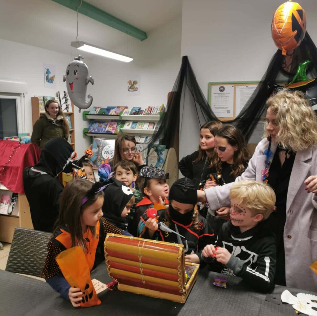 Enfants déguisés ouvrant un coffre rempli de surprises à la bibliothèque de Rochefort-Samson / Saint-Mamans lors de la chasse aux trésors d’Halloween 2025